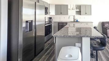 A modern kitchen with stainless steel appliances, a granite countertop, and a built-in dishwasher.