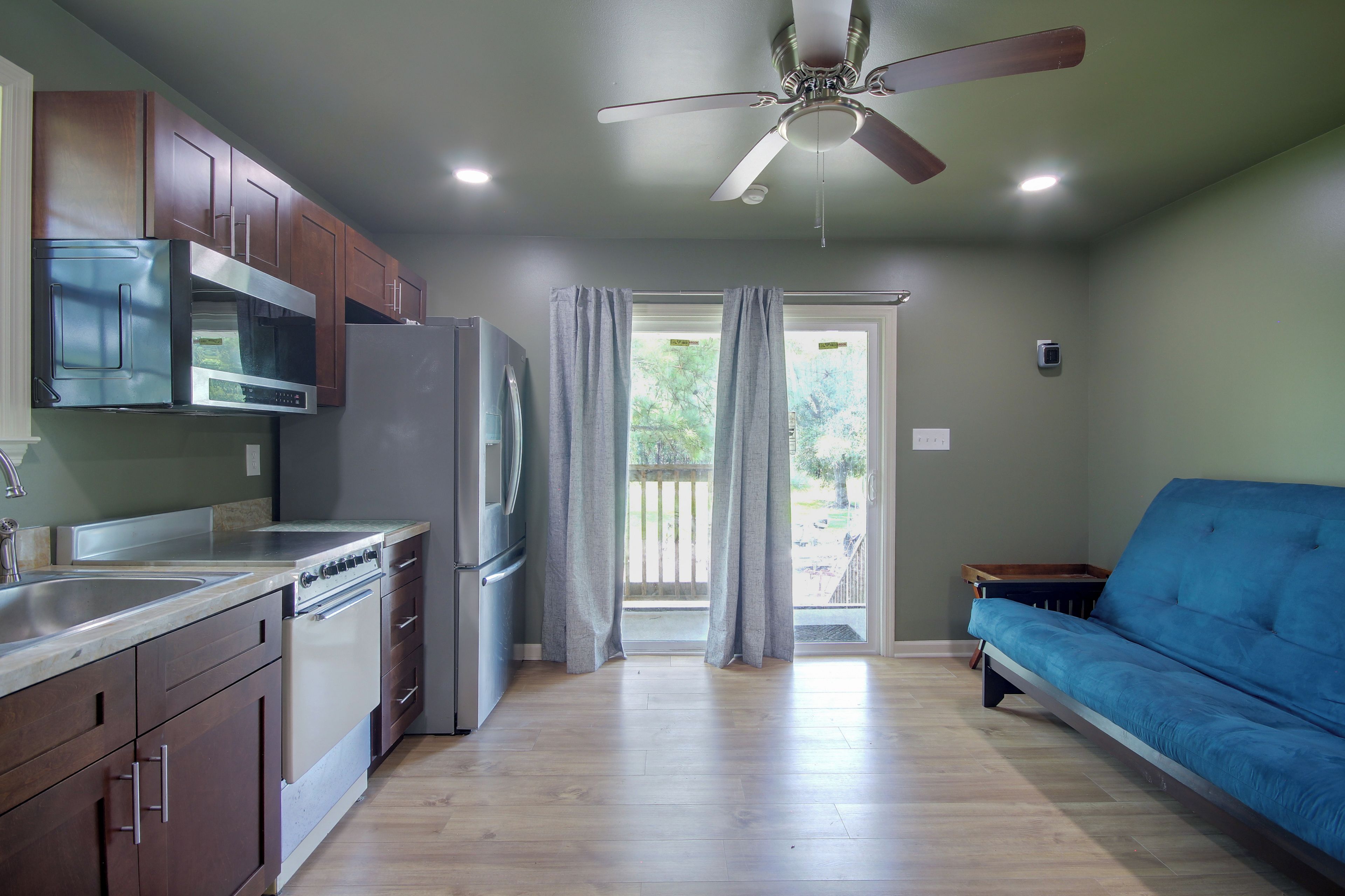 A kitchen with wooden cabinets, stainless steel appliances, a ceiling fan, and a view to the outside.