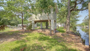 A covered outdoor area with a picnic table and a small building, surrounded by trees and a body of water.