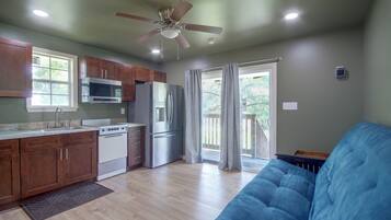 A kitchen with a microwave, oven, refrigerator, and a ceiling fan.