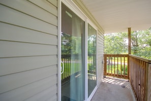 A covered porch with a wooden railing, a sliding glass door, and a view of a green landscape. - 4 Mi to Beach! Canal-front Escape in Bay St Louis (Bay St Louis)