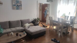 Una sala de estar moderna con un sofá gris, una mesa redonda y un comedor con mesa y sillas.