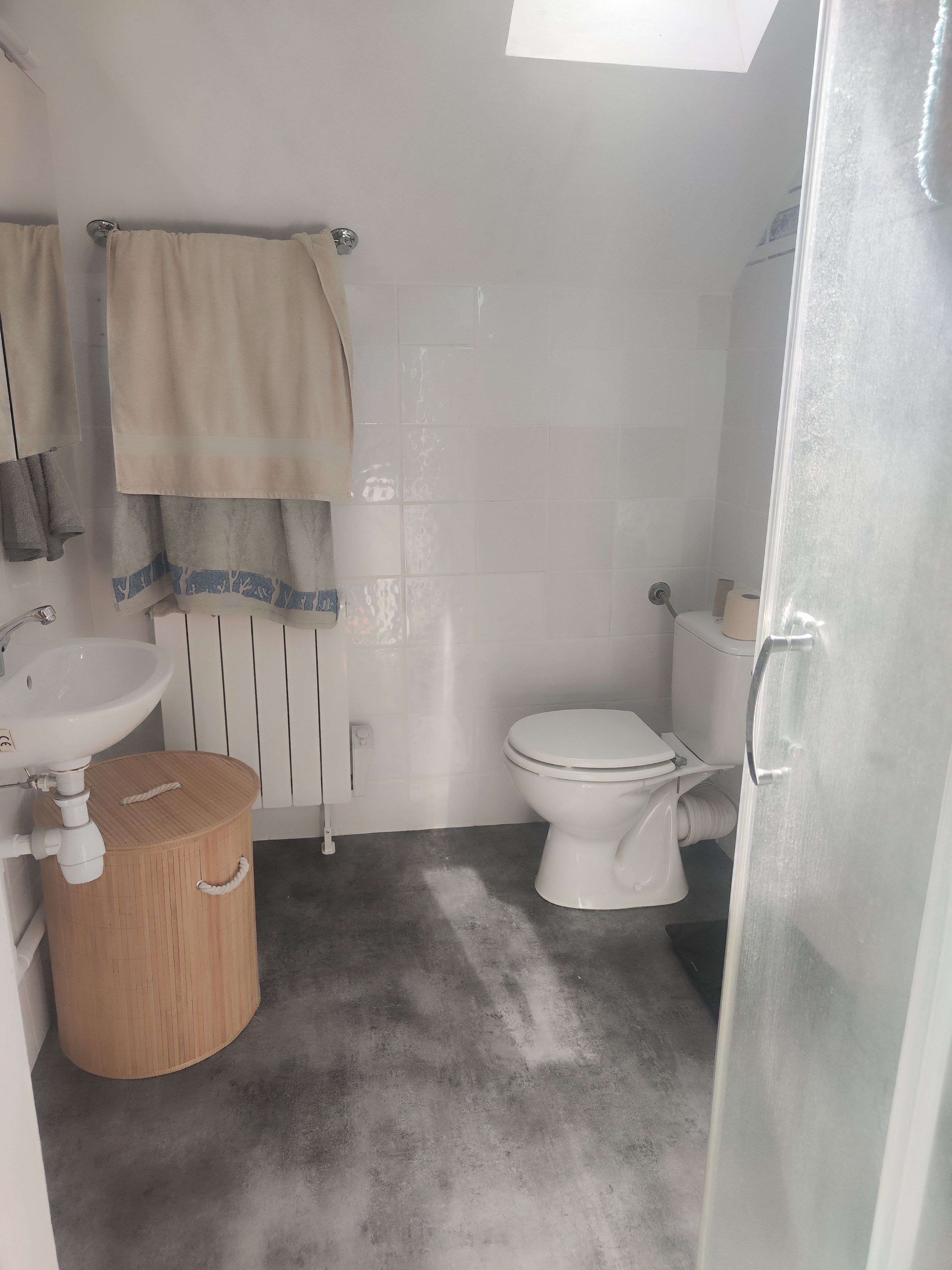 A bathroom with a white sink, toilet, and a wooden bucket.