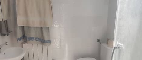 A bathroom with a white sink, toilet, and a wooden bucket.