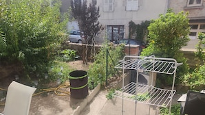 Un jardín con un tendedero de metal, un barril grande y una silla blanca.