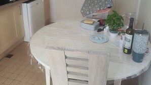 Una cocina con una mesa redonda, sillas, armarios, un lavamanos y varios electrodomésticos.
