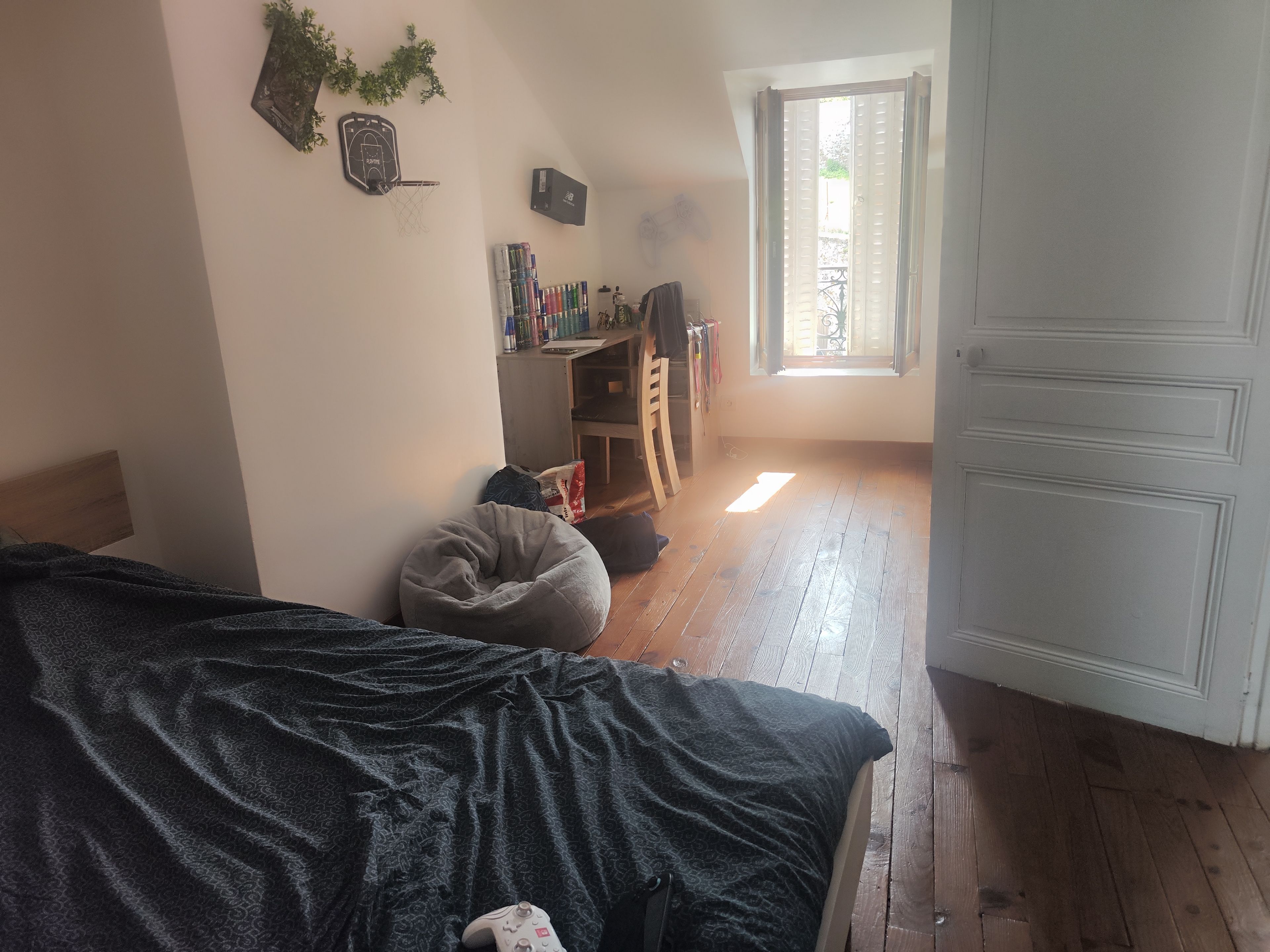 Une chambre à coucher avec un lit, un bureau, une chaise, une fenêtre et une porte.