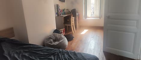 Un dormitorio con cama, escritorio, silla, ventana y puerta.