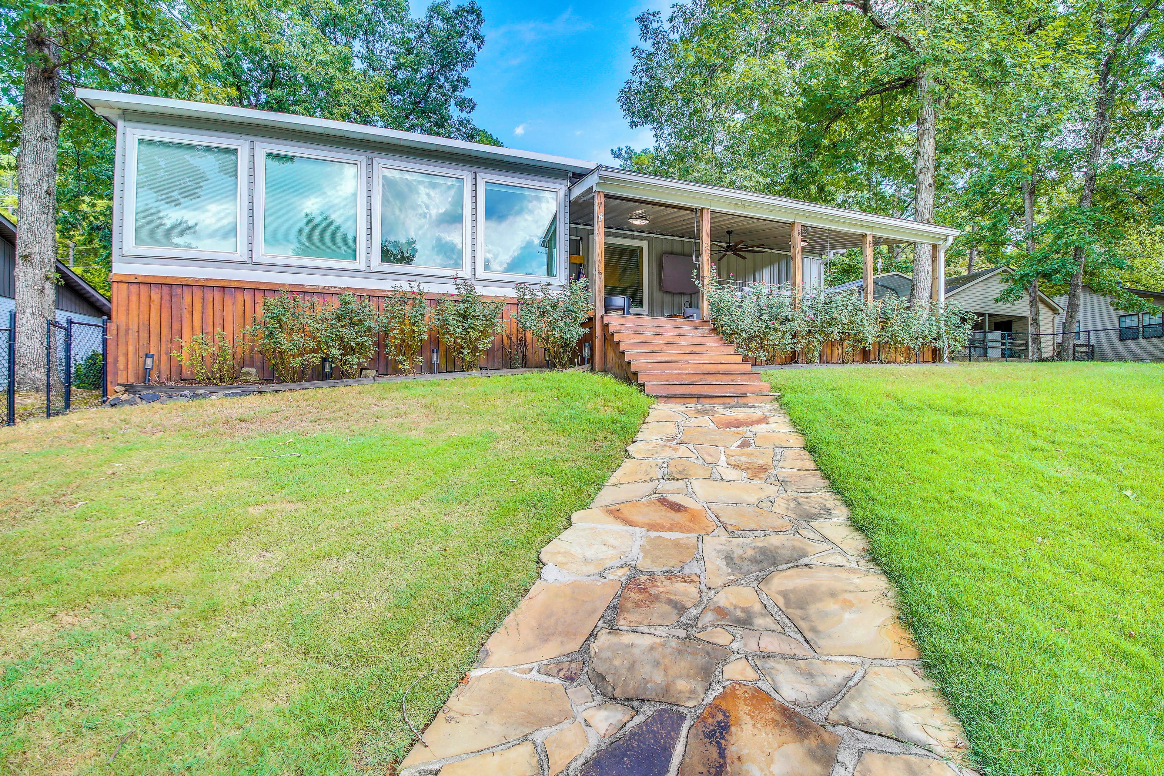 A modern house with a stone pathway leading to a wooden deck and a covered porch.