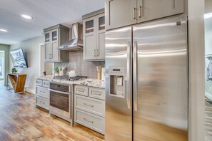 Une cuisine moderne dotée d’appareils électroménagers en acier inoxydable, de planchers en bois et d’un dosseret de carreaux disposés en motif chevrons.