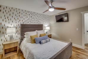 A bedroom with a bed, a nightstand, a lamp, a ceiling fan, and a TV on the wall. - Boat Dock & Game Room! Lake Hamilton Home (Hot Springs)