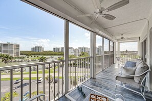 Ein Balkon mit Blick auf einen Yachthafen und die Skyline, möbliert mit einer Couch und Stühlen.