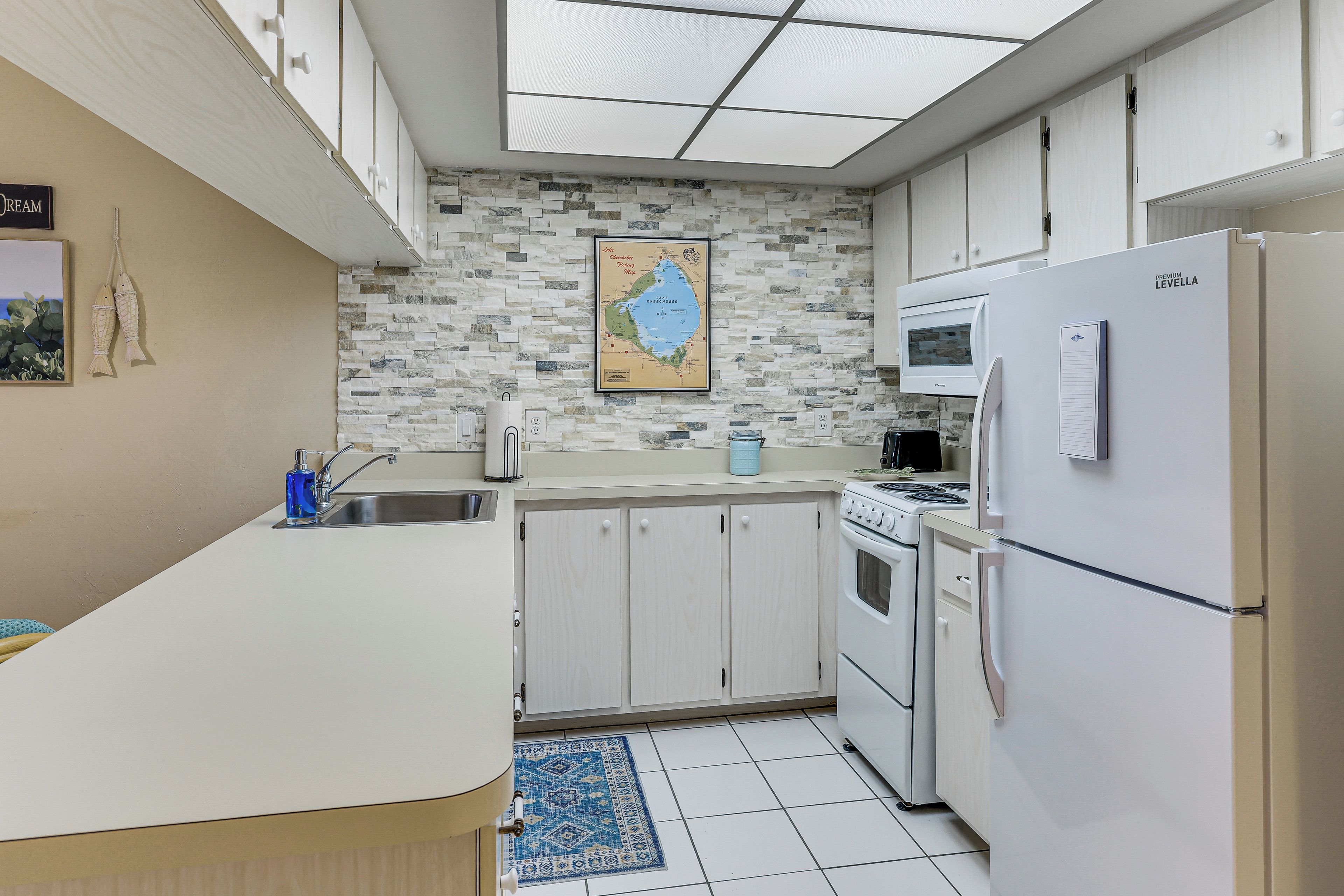 A compact kitchen with a white countertop, a stove, a refrigerator, and a microwave.