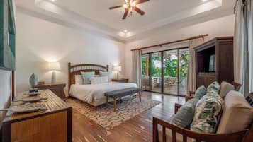 A spacious bedroom with a large bed, a wooden bench, a sofa, and a ceiling fan.