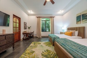 A bedroom with a bed, a desk, a television, and a window with curtains.