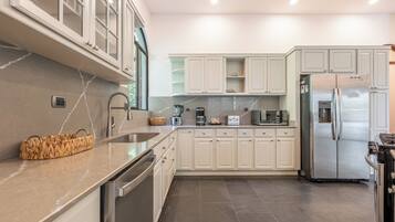 A modern kitchen with stainless steel appliances, a marble countertop, and light-colored cabinetry.