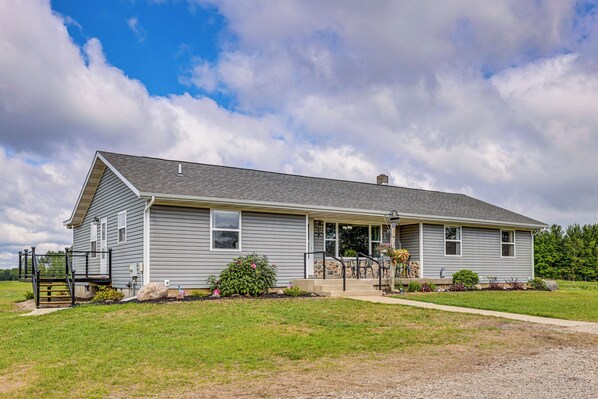 A single-story house with a front porch, a small garden, and a clear sky.