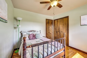 A bedroom with a wooden bed, a ceiling fan, and a door. - Fire Pit, Beautiful Wooded View, 70 Huntable Acres (Mecosta)