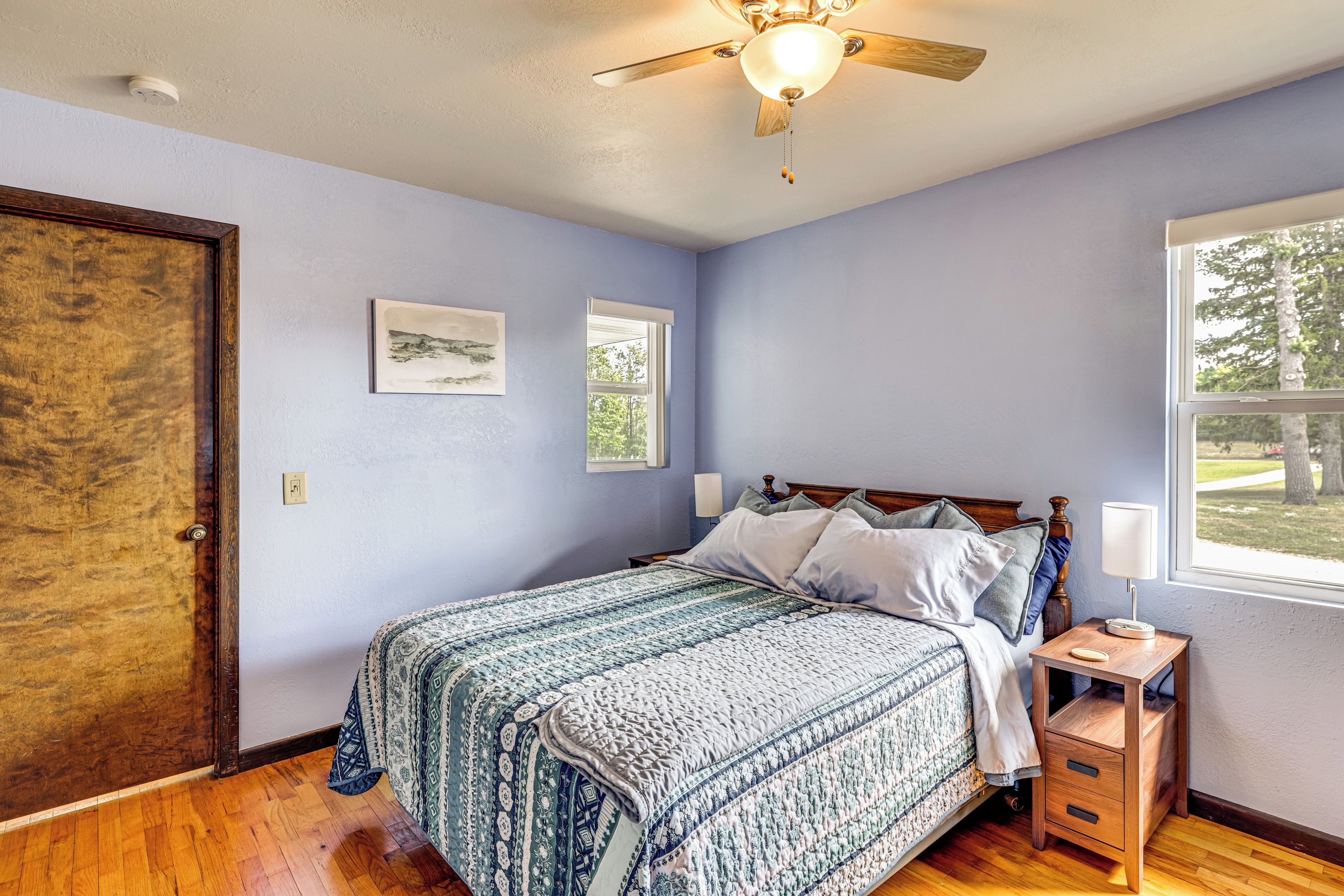 A bedroom with a bed, a nightstand, a window, and a ceiling fan.