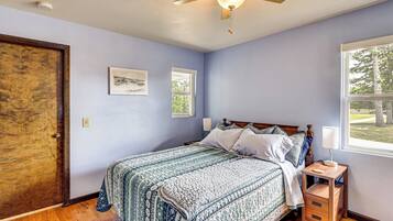 A bedroom with a bed, a nightstand, a window, and a ceiling fan.