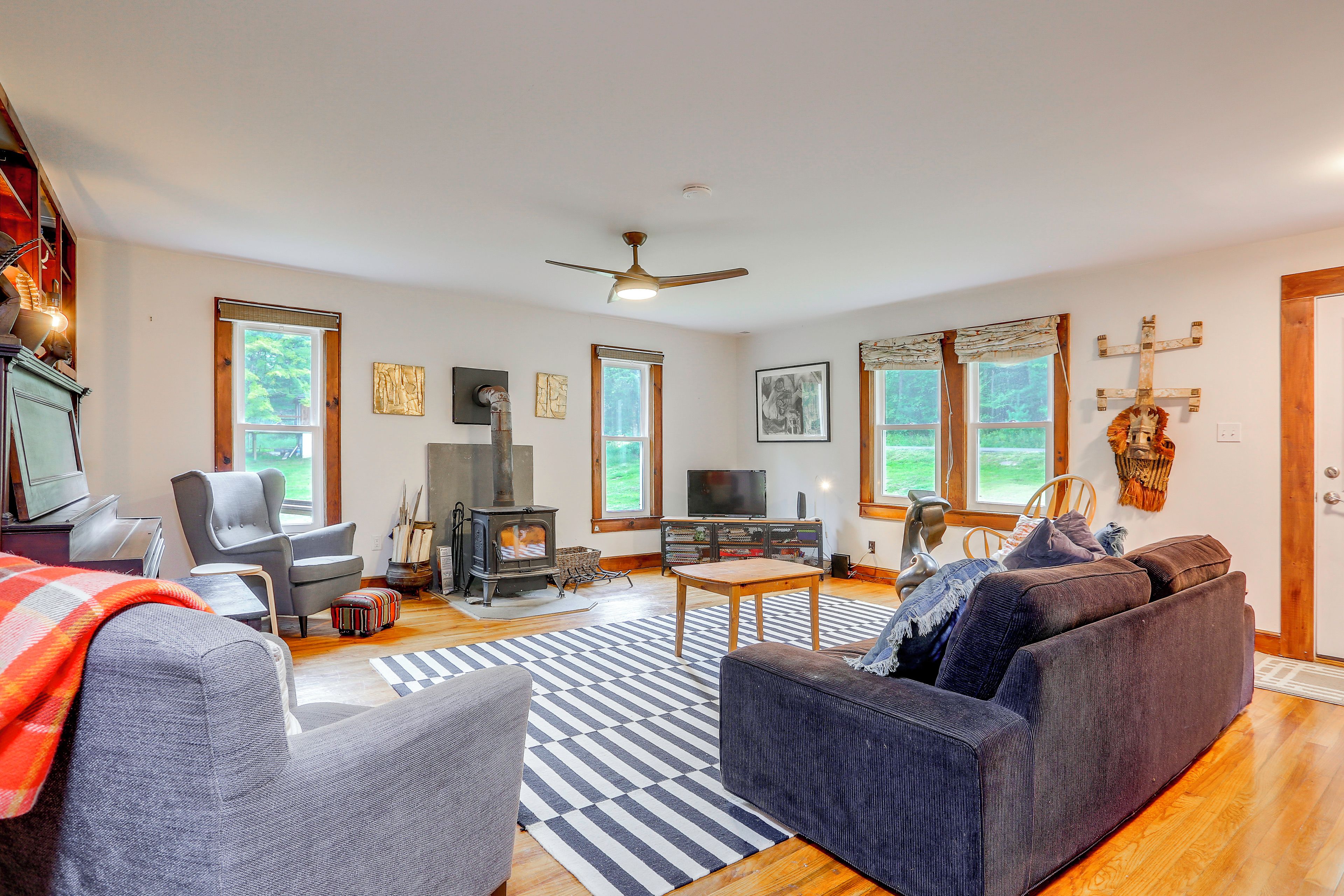 A cozy living room with a fireplace, comfortable seating, and large windows.