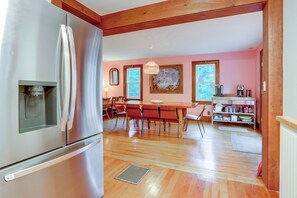 A kitchen with a stainless steel refrigerator, wooden dining table, and chairs.