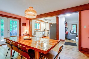 A spacious kitchen with a large wooden table, chairs, and a hanging light fixture.