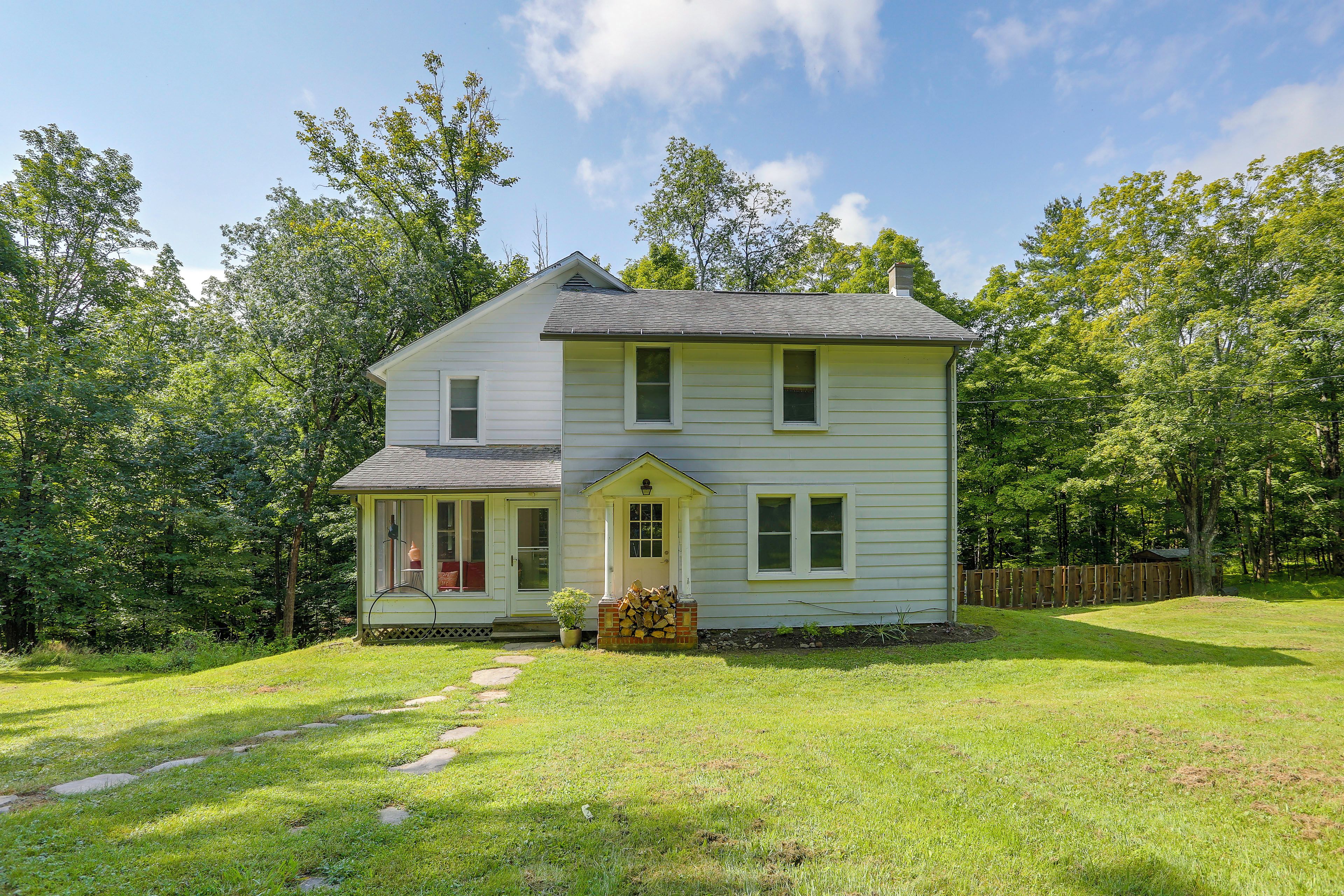 A two-story house with a front porch and a small garden area.