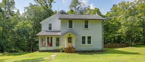 A two-story house with a front porch and a small garden area.
