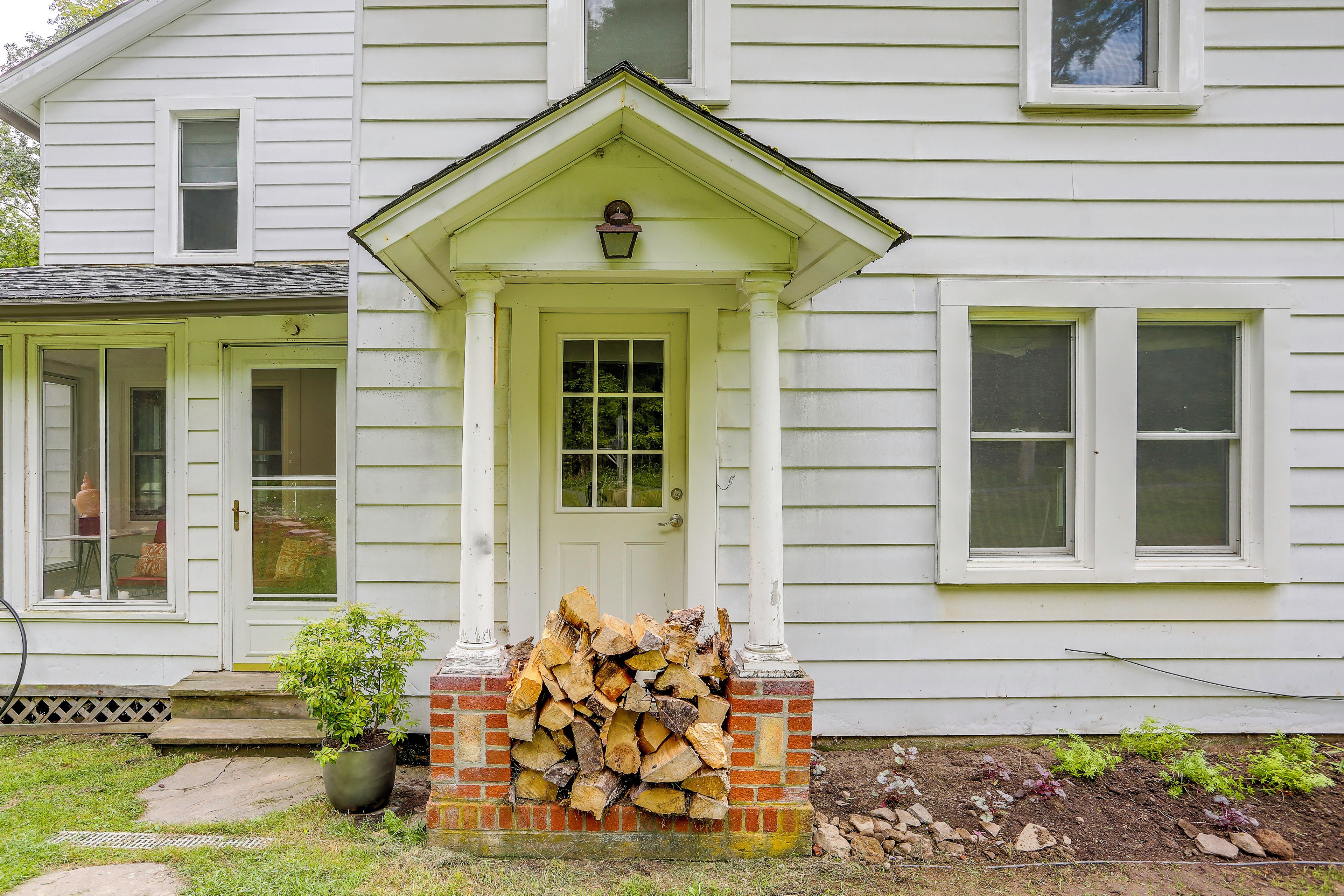 A house with a front door, a porch, and a stack of firewood.