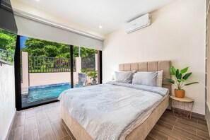 Une chambre avec un grand lit, une plante en pot et une vue sur une piscine.