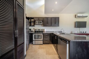 A modern kitchen with stainless steel appliances, dark cabinetry, and a granite countertop. - Sunny 2br: Balcony, Pool, Kitchen, Walk to Beach (Sardinal)