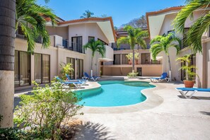 A pool area with lounge chairs and palm trees. - Sunny 2br: Balcony, Pool, Kitchen, Walk to Beach (Sardinal)