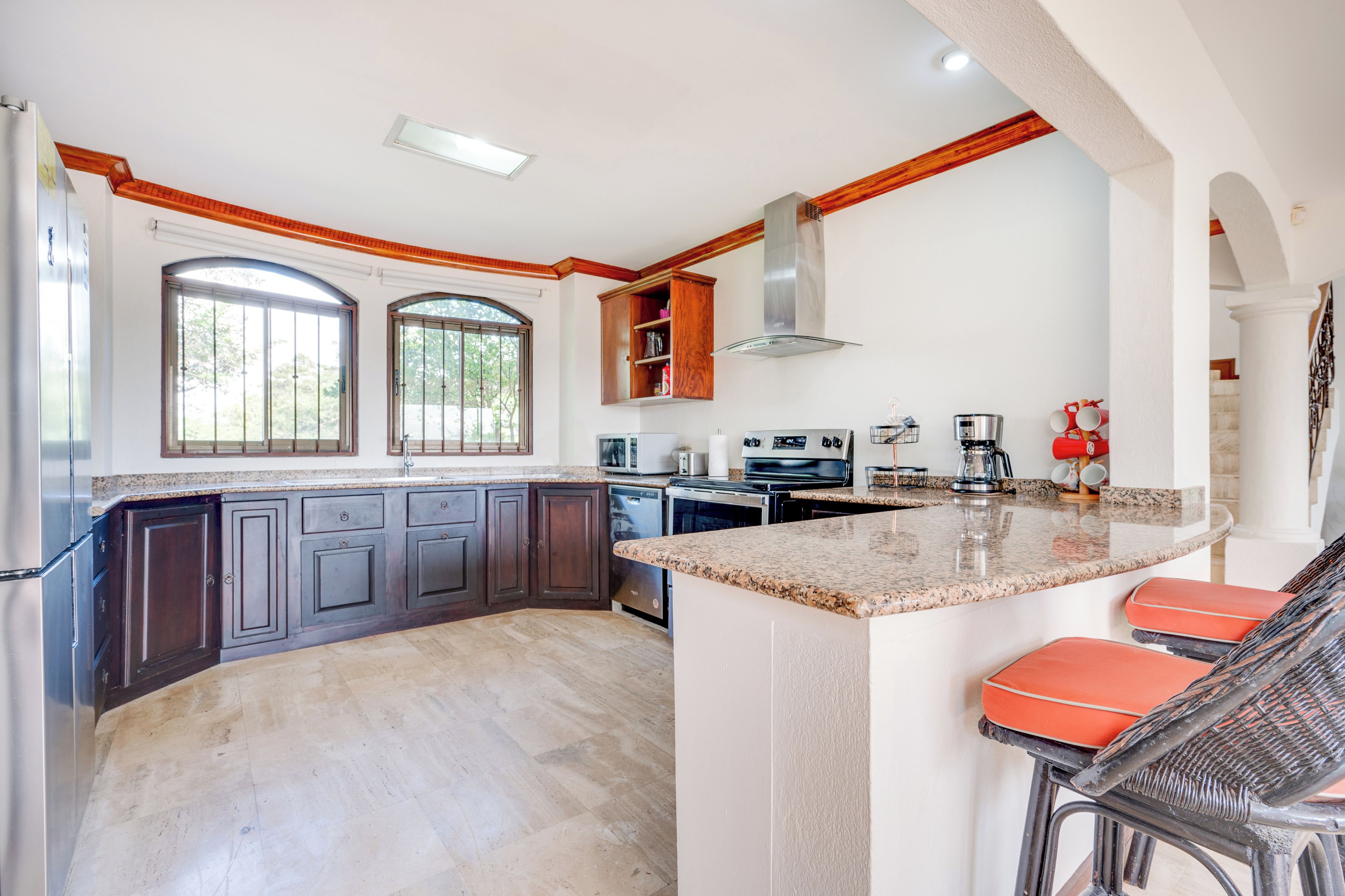 A spacious kitchen with dark cabinetry, a large island with bar stools, and a view through the windows.
