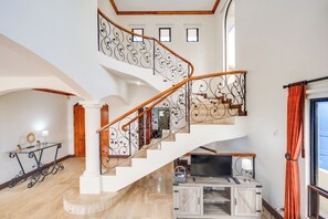 A multi-level interior with a staircase, a flat-screen TV, and a wooden cabinet.