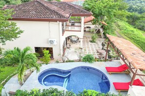 A two-story house with a swimming pool, outdoor seating, and a garden.