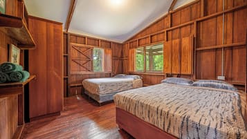 A wooden room with two beds, a large window, and a door leading outside.