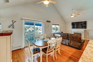 A dining area with a table and chairs, a kitchen with a stove, and a living area with a sofa and TV.