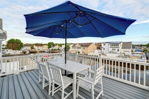 A deck with a table and chairs, a blue umbrella, and a view of houses.