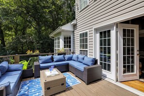 A deck with a sectional sofa, a wicker ottoman, and a coffee table. - Walk to Herrington Harbor: Spacious Bay Home (Tracys Landing)