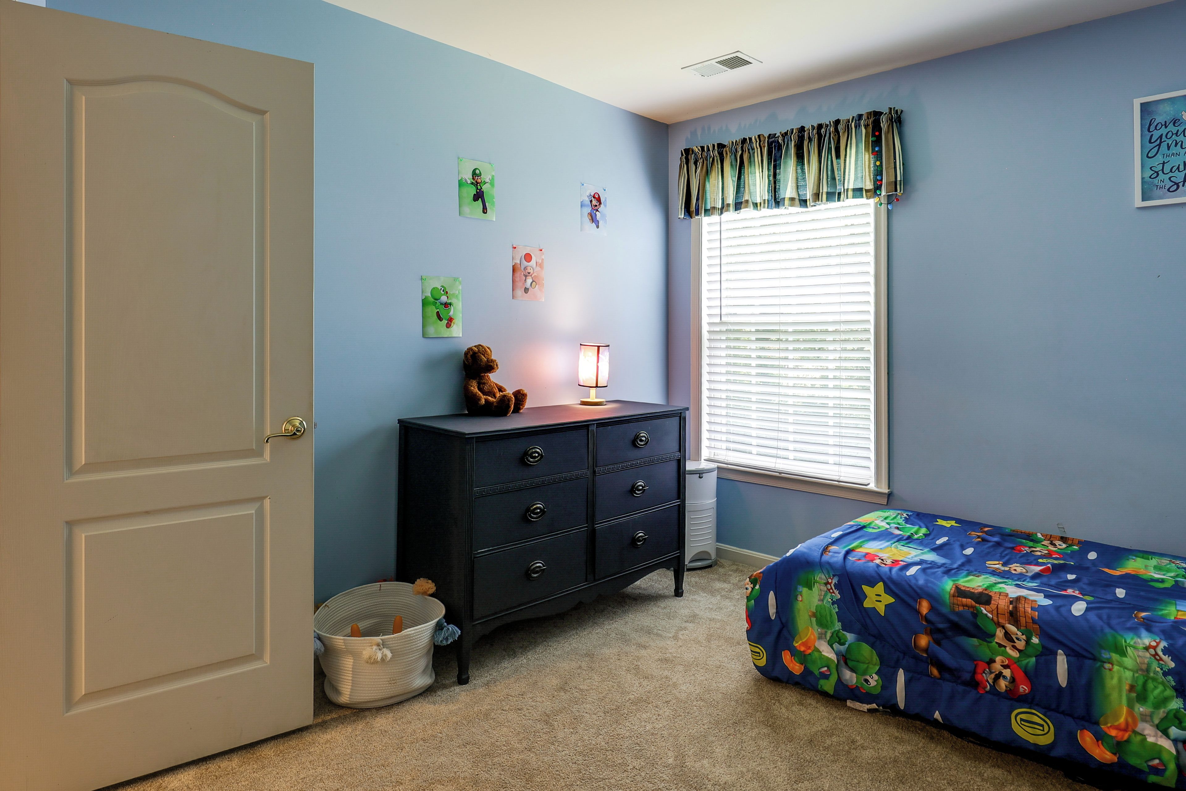 A bedroom with a bed, dresser, and wall decorations.