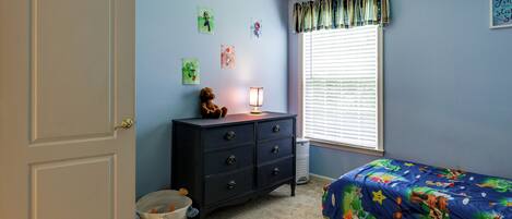 A bedroom with a bed, dresser, and wall decorations.