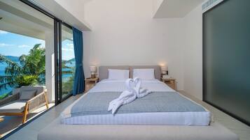 Una habitación de hotel moderna con una cama grande, vistas al mar y un balcón con una silla.