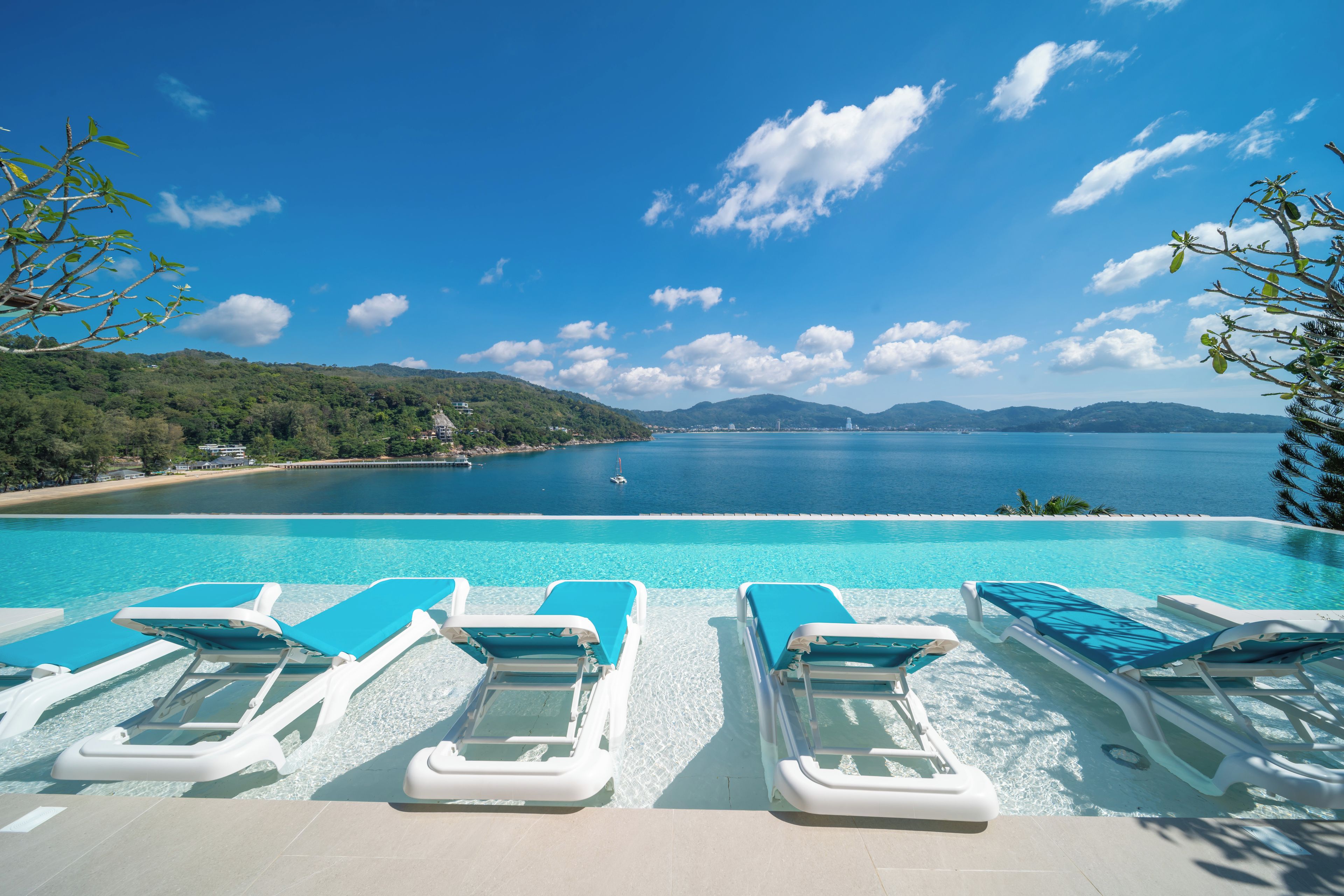Zona junto a la piscina con sillones de descanso y vista al mar.