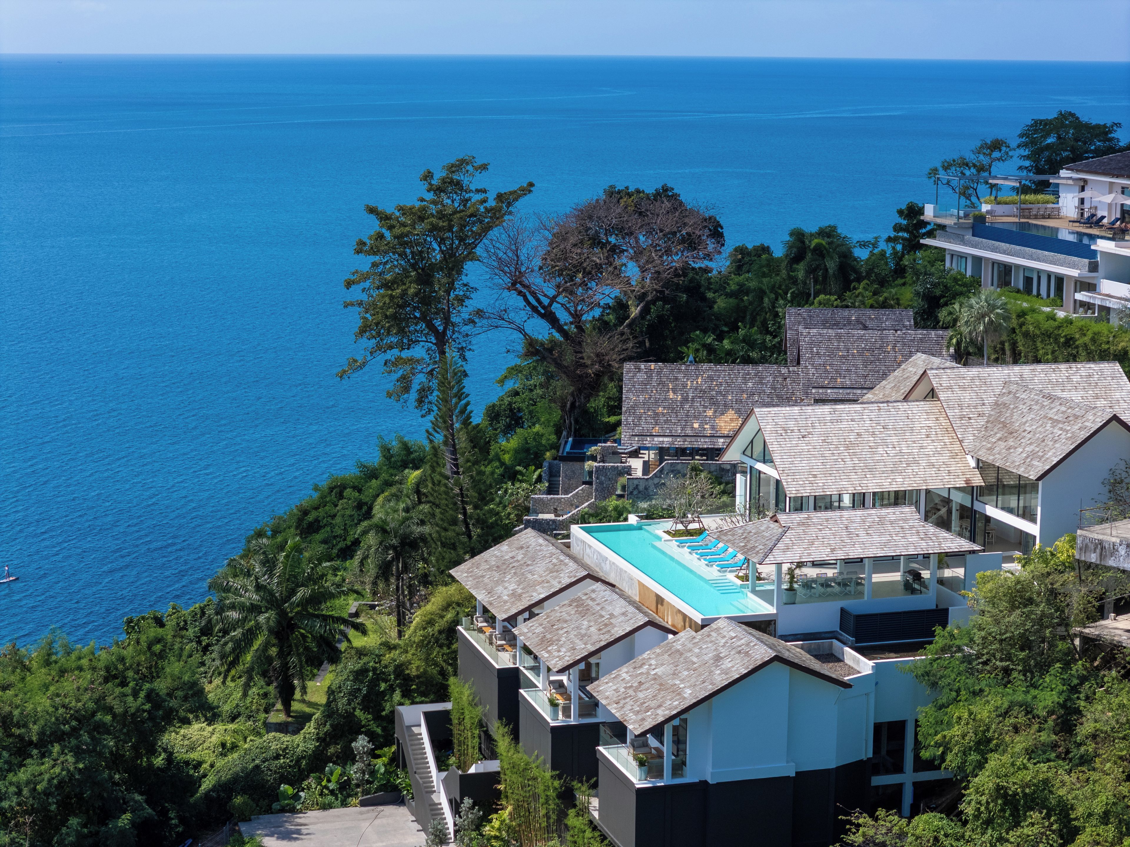Una propiedad costera moderna con piscina, varias edificaciones y vista al mar.