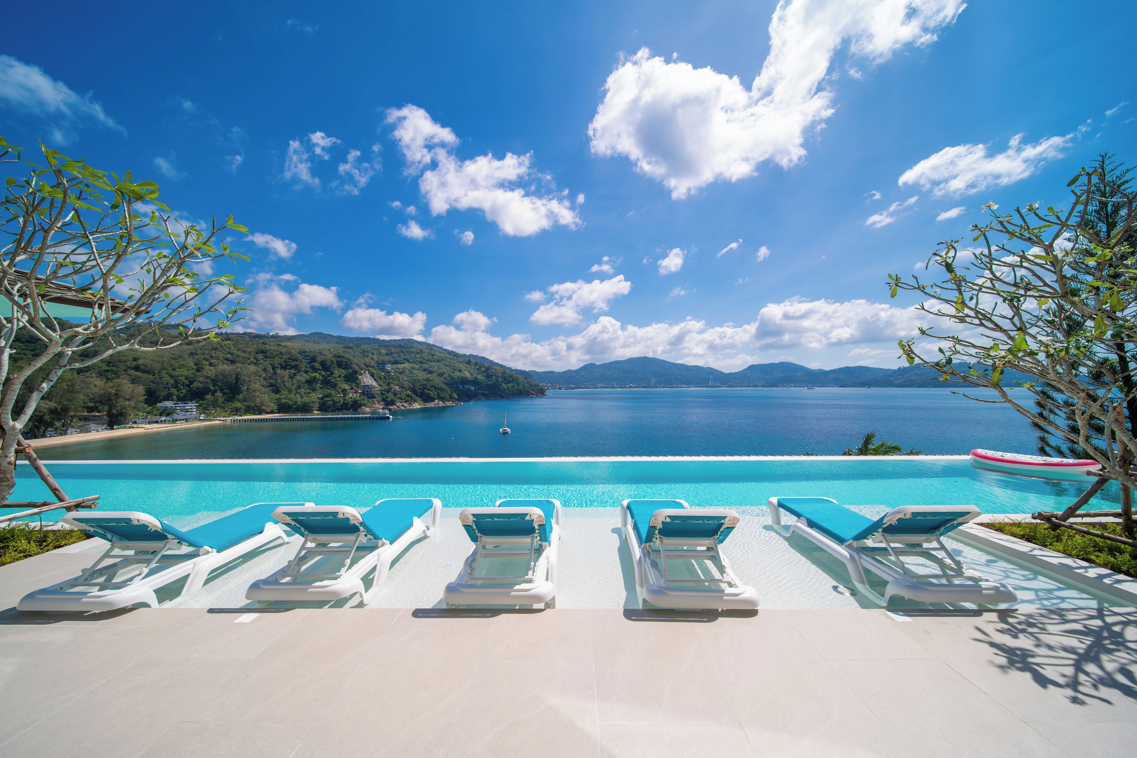 Vista a la piscina con sillones de descanso y una vista despejada del mar y las montañas.