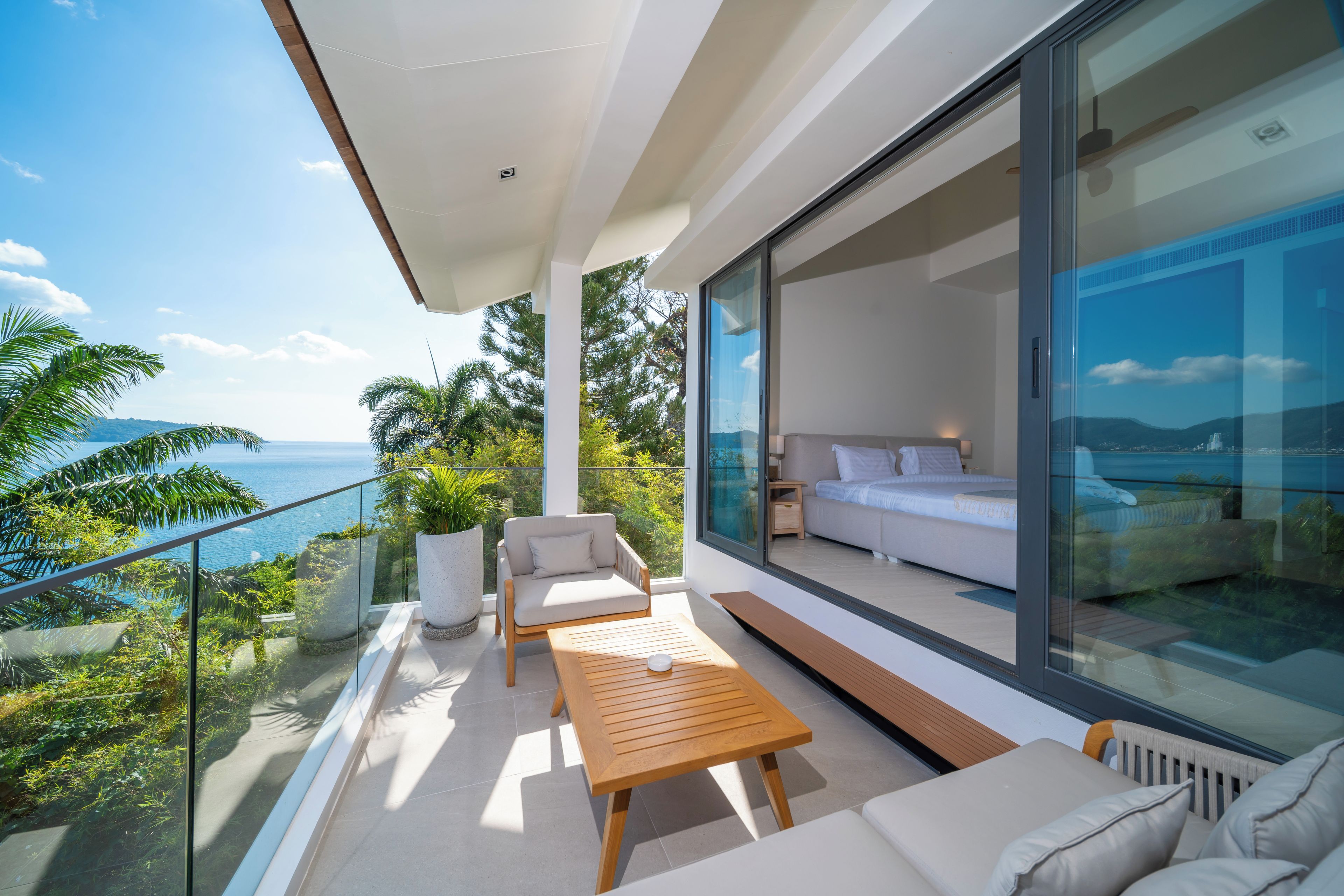 A modern balcony with a sofa, a wooden table, and a potted plant.