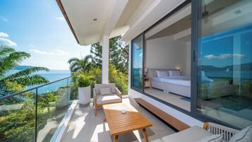 A modern balcony with a sofa, a wooden table, and a potted plant.