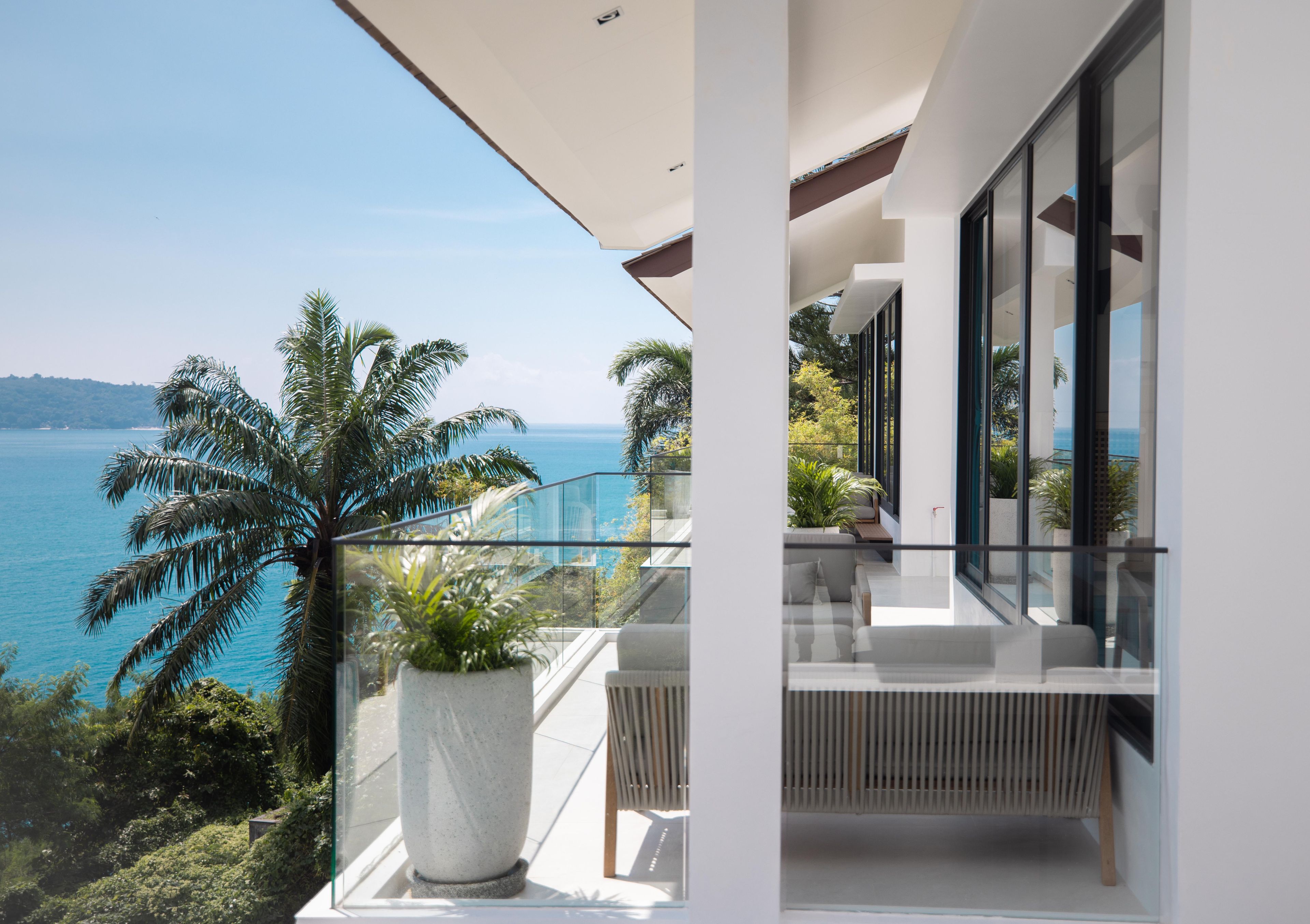 Un balcón con vista al mar y palmeras.