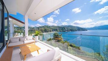 Een balkon met uitzicht op een meer en bergen, voorzien van een bank, tafel en stoelen.
